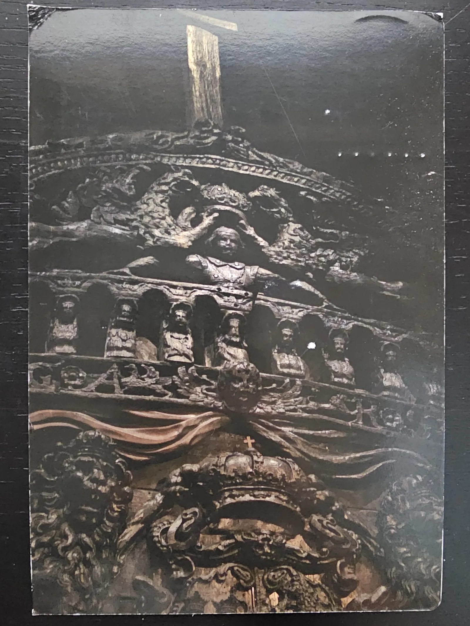 Eine dunkle, detailreiche Holzschnitzerei am Heck der Vasa zeigt eine Krönungsszene, Reihen von Figuren und üppige barocke Verzierungen.