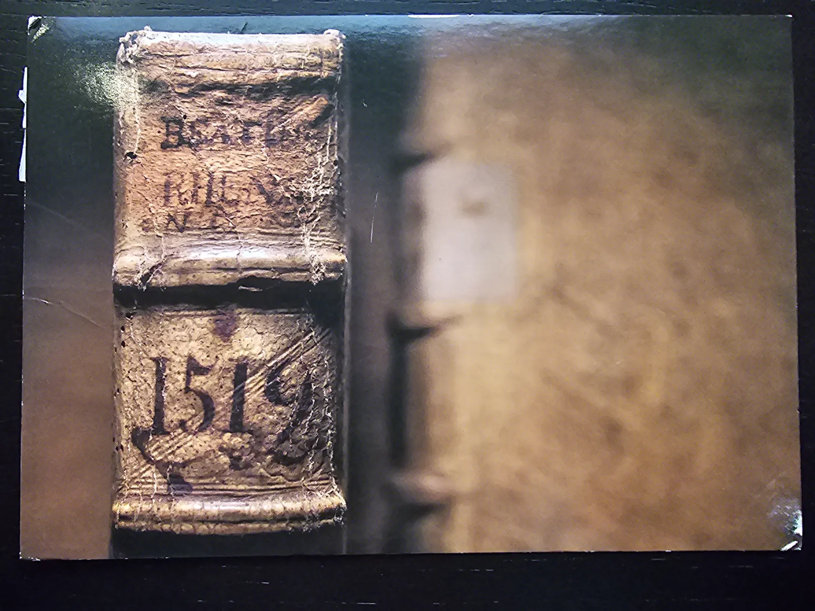 Ein alter, stark abgenutzter Buchrücken mit verblasster Schrift und der Zahl „1512“ ist vor einem unscharfen, warmen Hintergrund abgebildet.