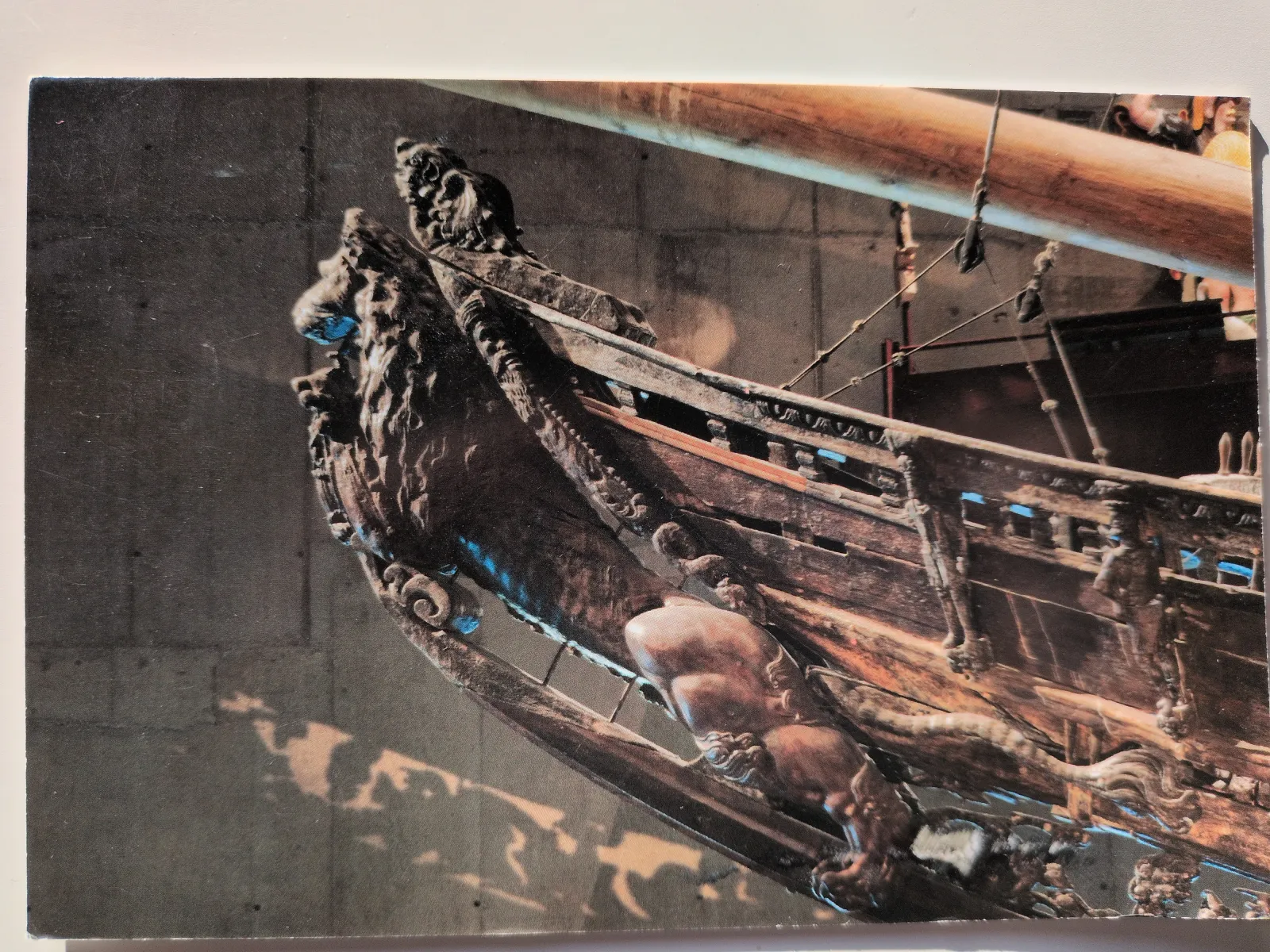 Eine Nahaufnahme zeigt eine dunkle, detailreich geschnitzte Holzskulptur mit Figuren, die an den Bug eines alten Schiffes erinnert.