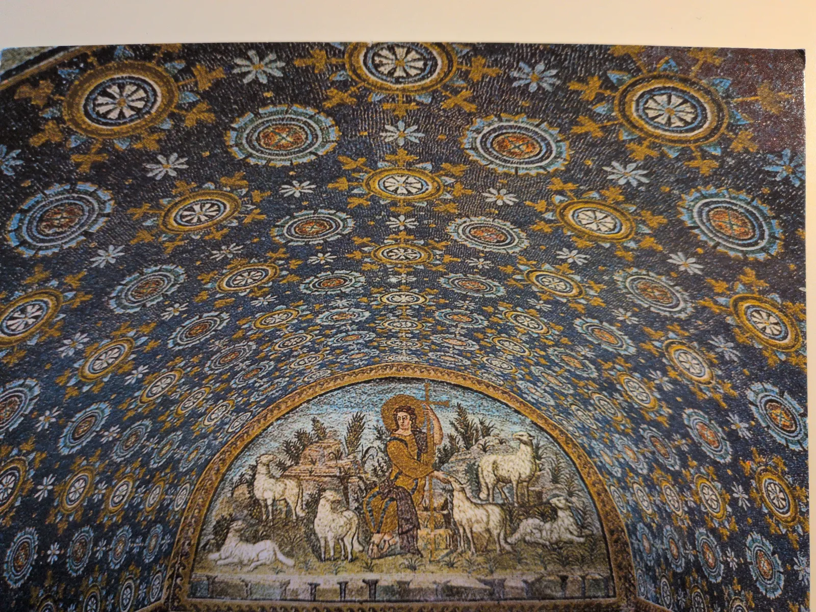 Ein Mosaik einer gewölbten Decke zeigt den Guten Hirten mit Schafen, umgeben von dunklen, gold- und blau gemusterten Ornamenten.