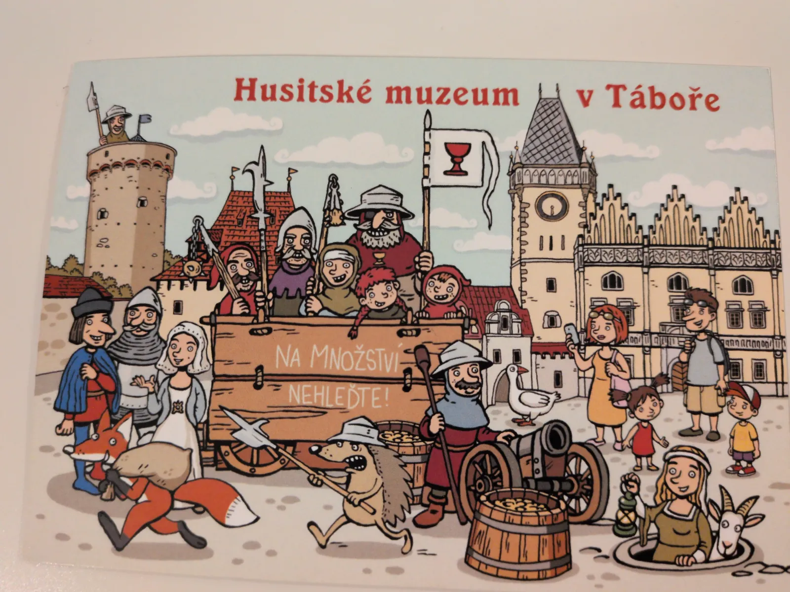 Ein farbenfrohes Cartoon-Bild des Hussitenmuseums in Tábor zeigt eine lebhafte Szene mit historischen Figuren, Tieren und Touristen.