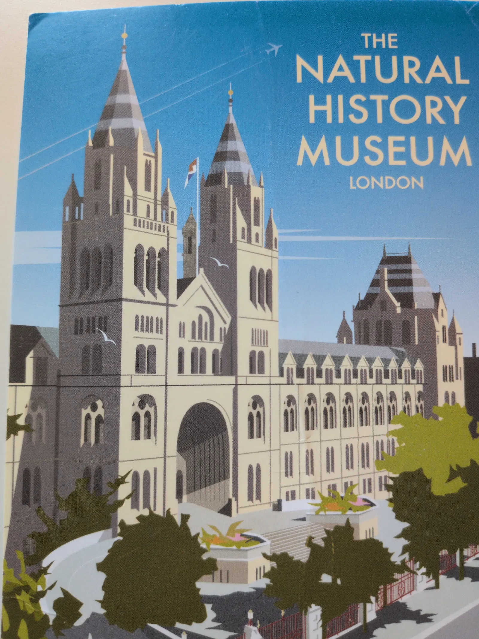 Eine stilisierte Illustration des Natural History Museum in London mit seinen markanten Türmen unter blauem Himmel.