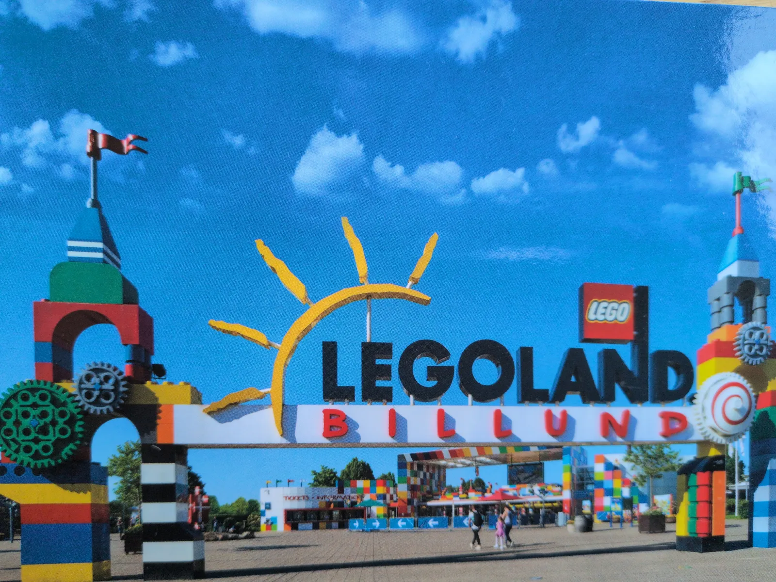 Ein großer, bunter Eingangsbogen aus Lego-Bausteinen mit dem Schriftzug „LEGOLAND BILLUND“ empfängt Besucher unter blauem Himmel.
