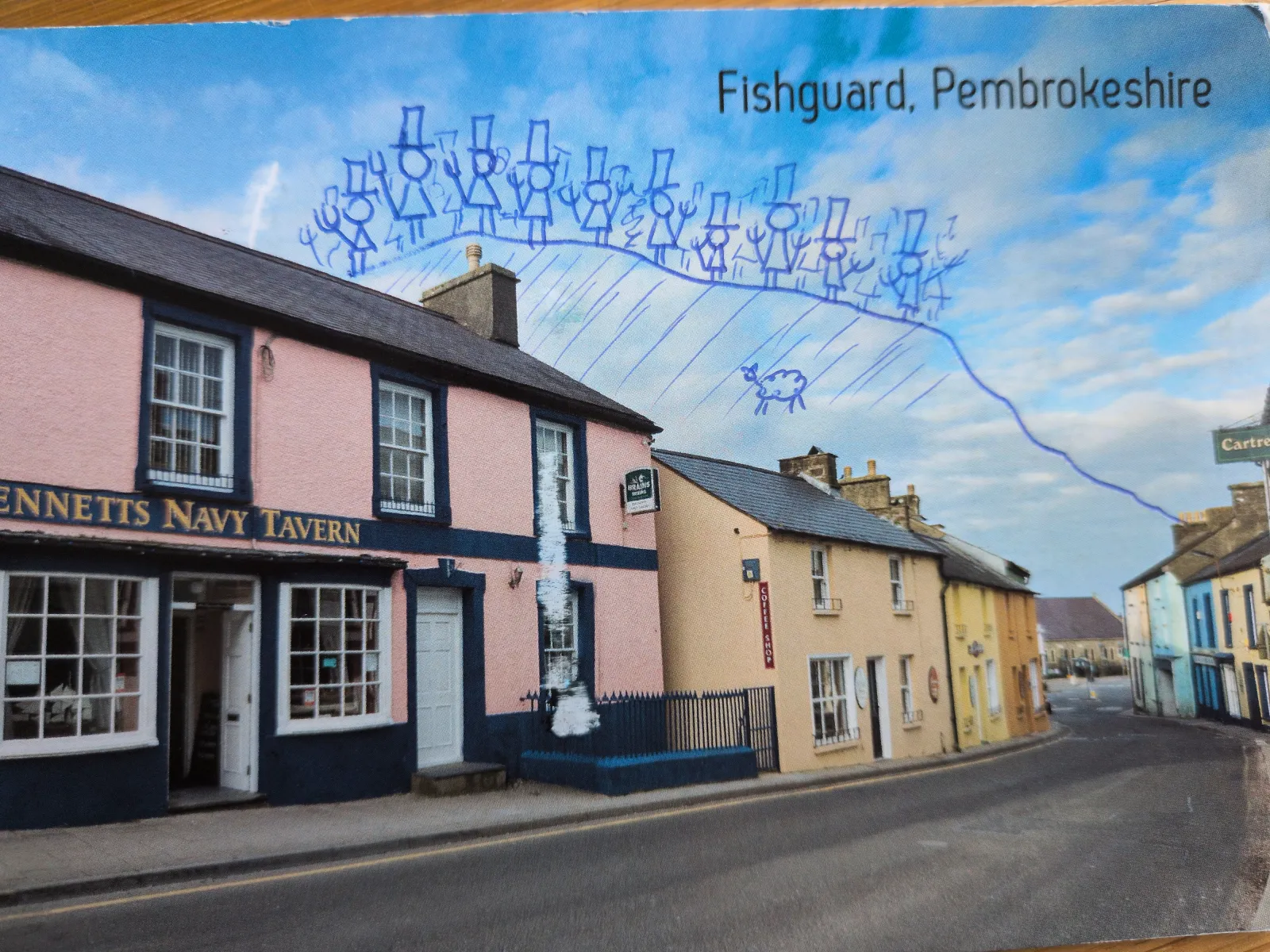 Ein Straßenbild aus Fishguard, Pembrokeshire, mit bunten Häusern, überzeichnet mit blauen Strichmännchen mit Zylindern und einem Schaf.
