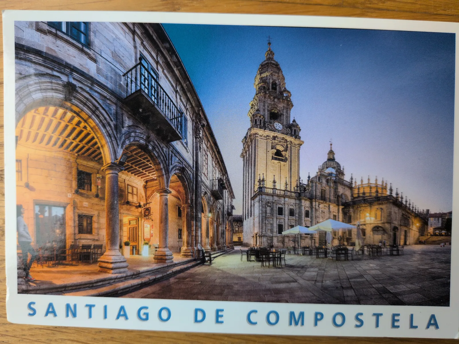 Ein abendlicher Blick auf den beleuchteten Platz von Santiago de Compostela mit seiner großen Kathedrale und den angrenzenden Arkadengebäuden.