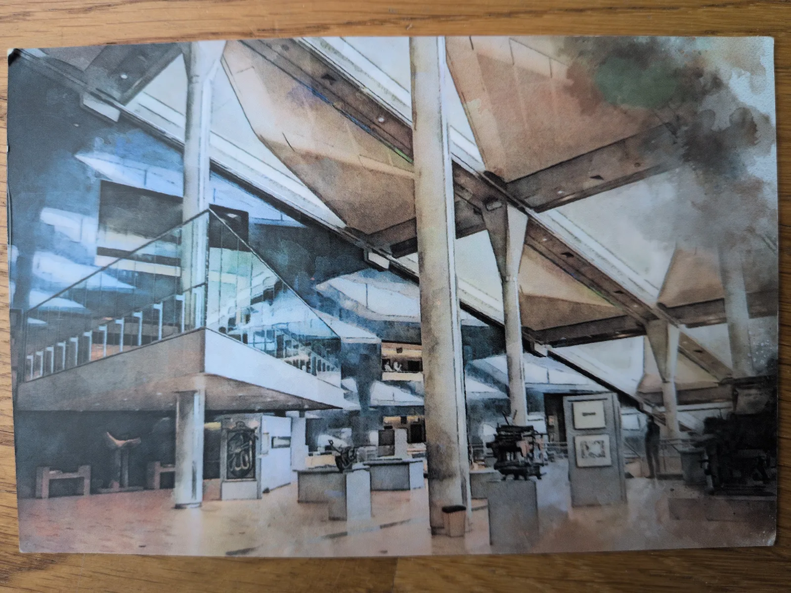 Ein weitläufiger, moderner Museumsinnenraum mit hohen, architektonisch markanten Decken, einer gläsernen Treppe und Kunstobjekten auf mehreren Ebenen.