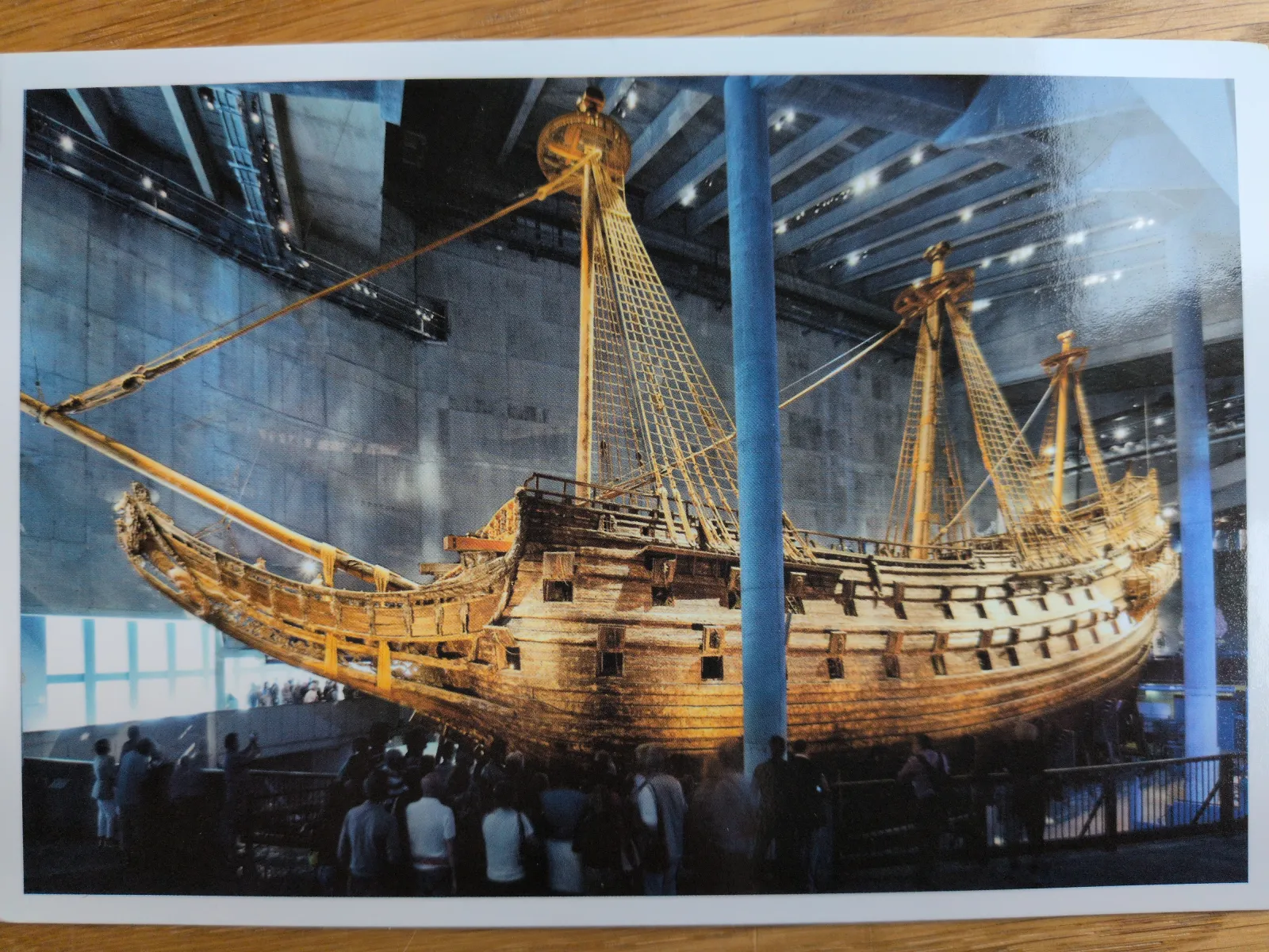 Ein imposantes, altes Holzschiff mit hohen Masten und Takelage steht in einer großen Museumshalle, umgeben von zahlreichen Besuchern.