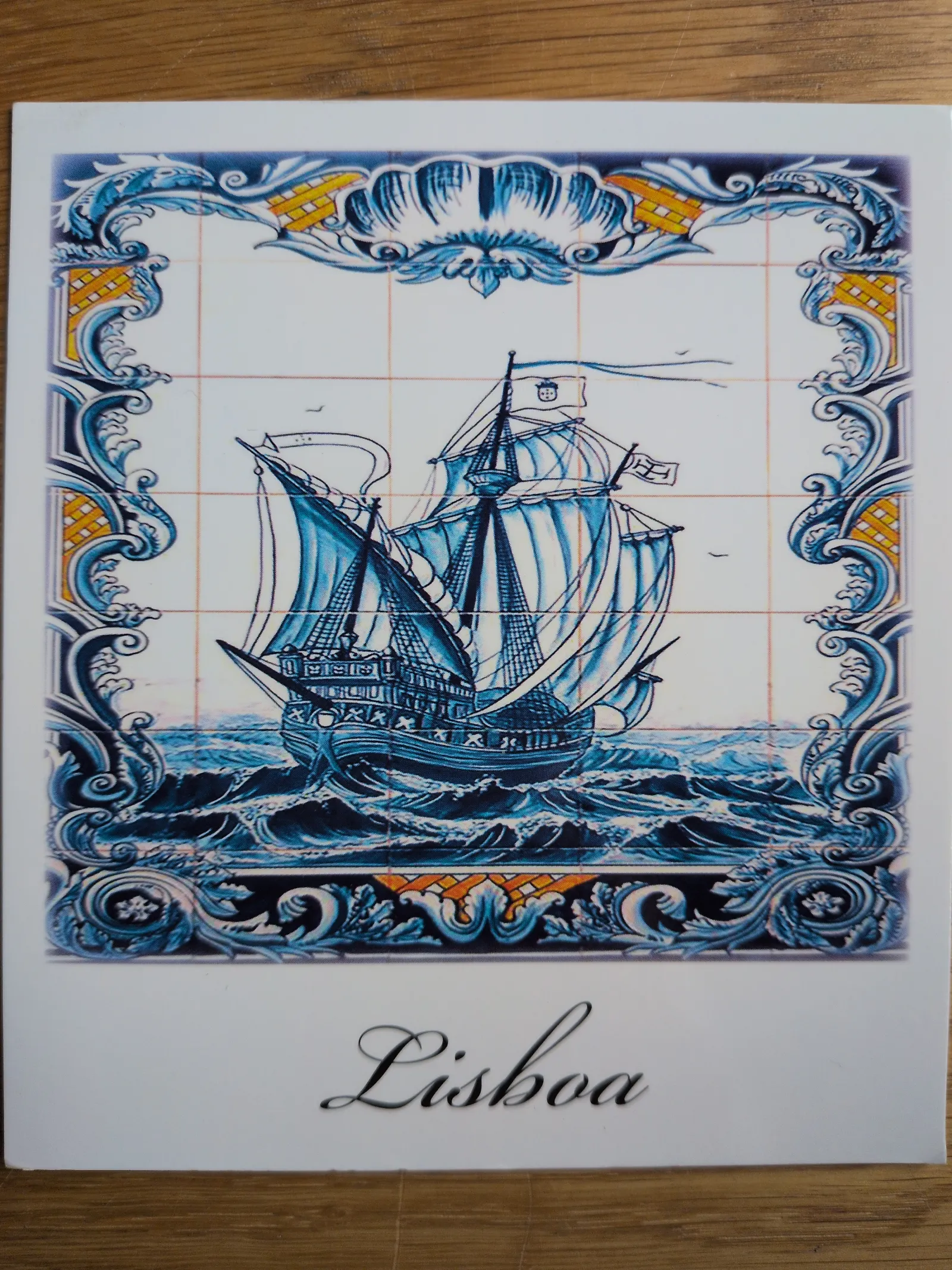 Ein blau-weißes Azulejo-Bild zeigt ein Segelschiff auf hohen Wellen, umrahmt von Ornamenten, mit dem Schriftzug "Lisboa" am unteren Rand.