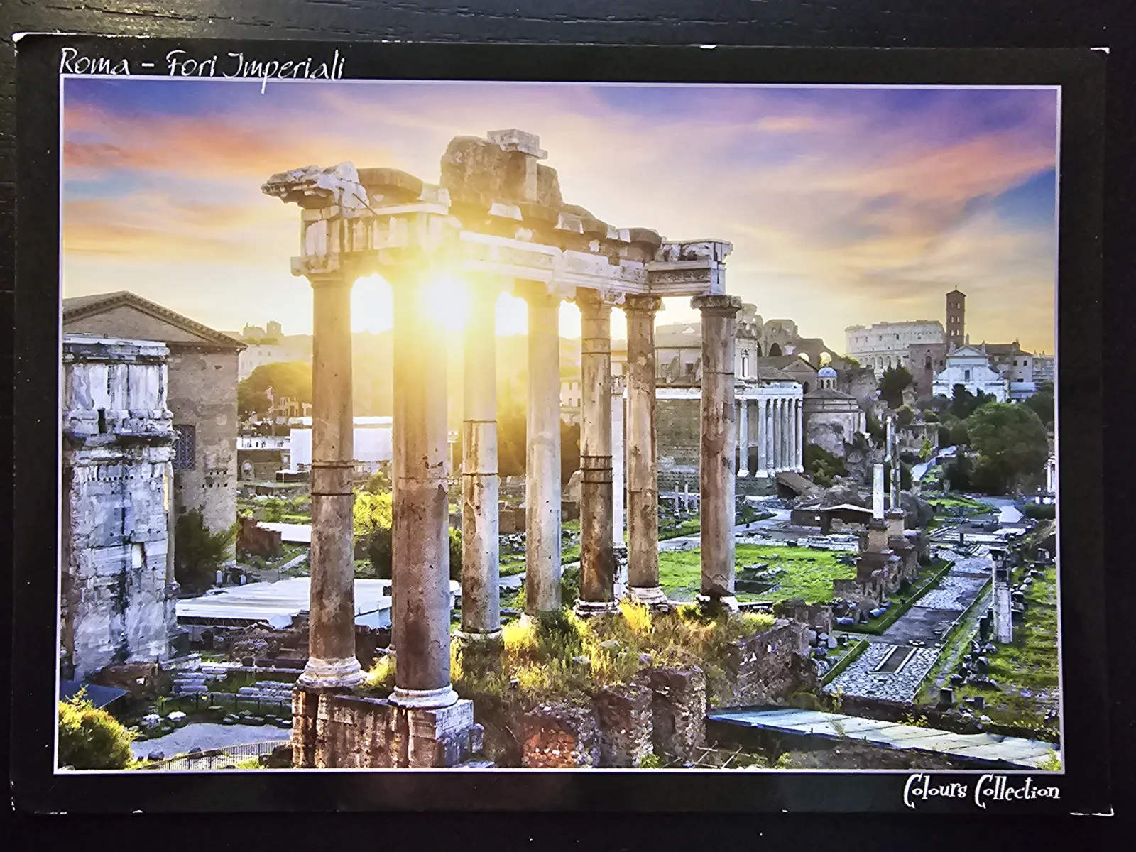 Das Bild zeigt die Ruinen des Forum Romanum in Rom, wo die helle Abendsonne durch antike Säulen bricht und den Himmel in warmen Farben leuchten lässt.