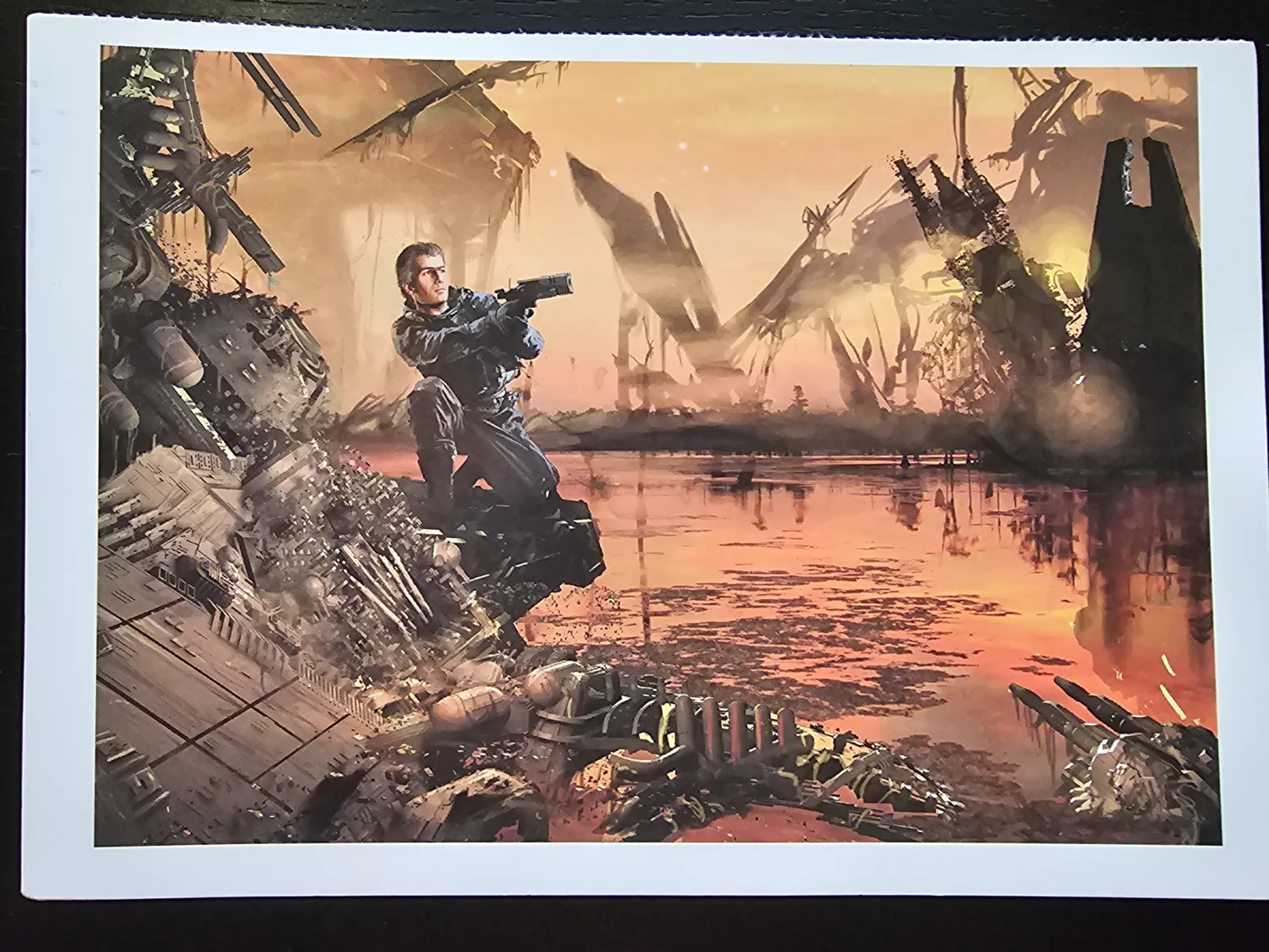 Ein bewaffneter Mann kniet in einer post-apokalyptischen Trümmerlandschaft vor einem dramatischen Sonnenuntergang, der sich im Wasser spiegelt.