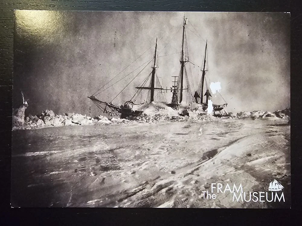 Ein Schwarz-Weiß-Foto zeigt ein dreimastiges Segelschiff, das von dicken Eisschollen in einer weiten, eisigen Landschaft umgeben ist.