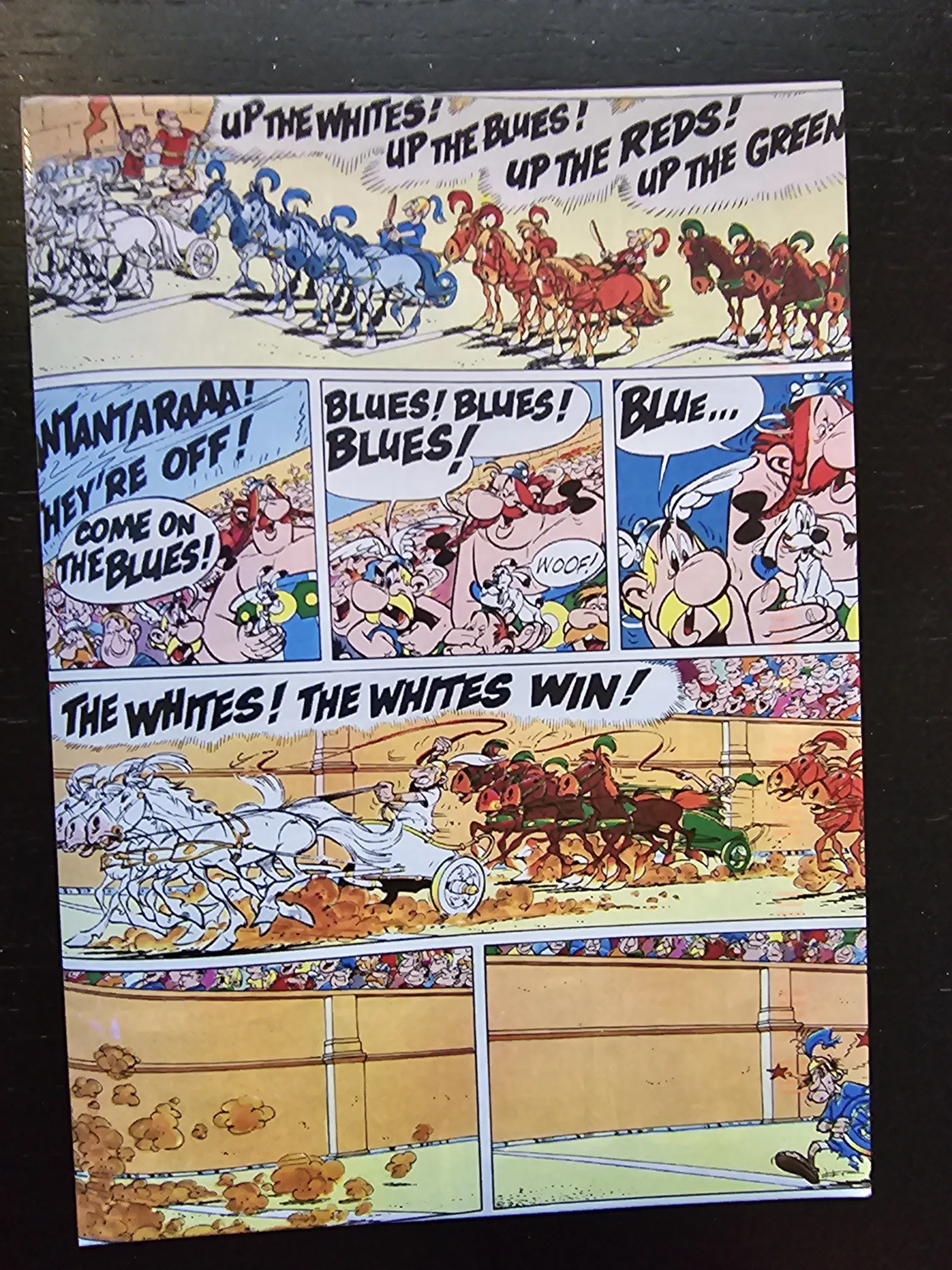 Eine Comicseite zeigt ein Wagenrennen in einem Stadion, bei dem die weißen Pferde gewinnen und Zuschauer jubeln.