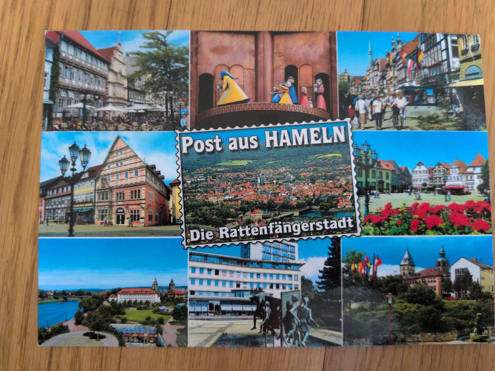 Das Bild ist eine Postkarten-Collage mit verschiedenen Ansichten von Hameln, darunter historische Gebäude, Stadtpanoramen und Darstellungen der Rattenfänger-Legende.