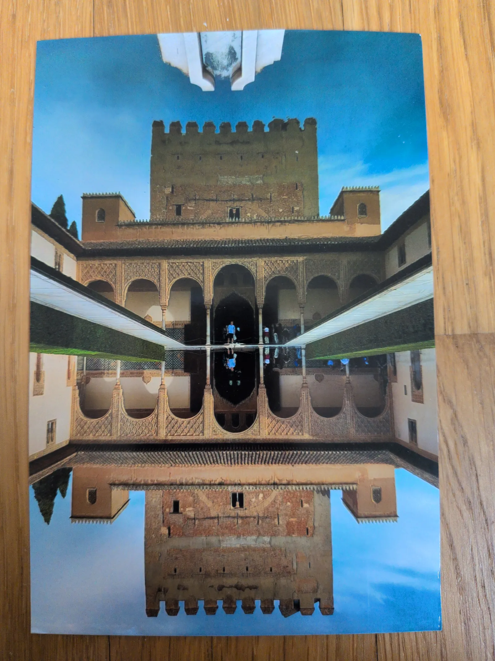 Ein maurischer Palasthof mit einem langen Wasserbecken, das die Architektur und einen Turm perfekt spiegelt.