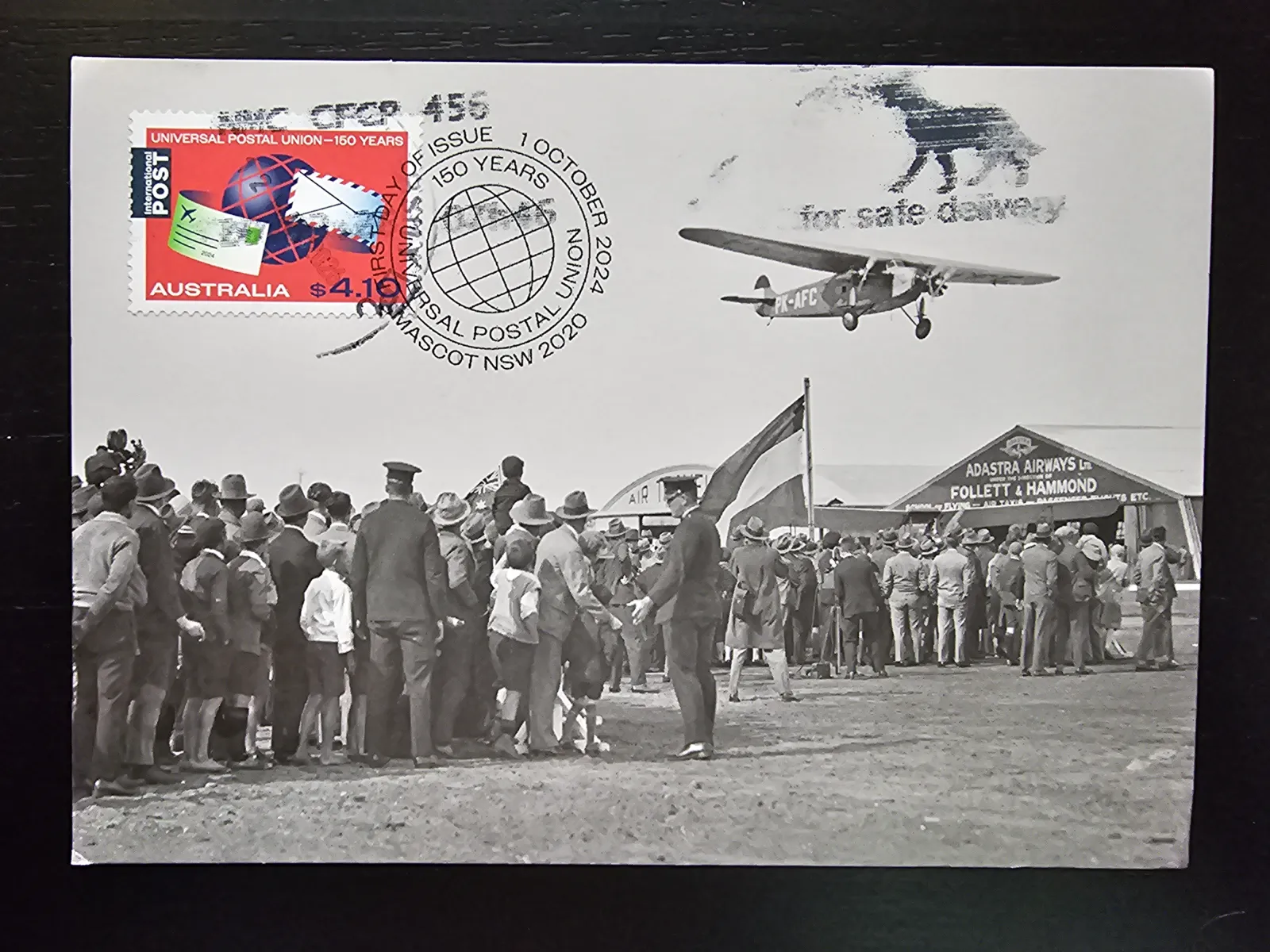 Ein australischer Ersttagsbrief mit einer Briefmarke zum Weltpostverein zeigt ein Schwarz-Weiß-Foto einer Menschenmenge, die ein Propellerflugzeug auf einem Flugfeld beobachtet.