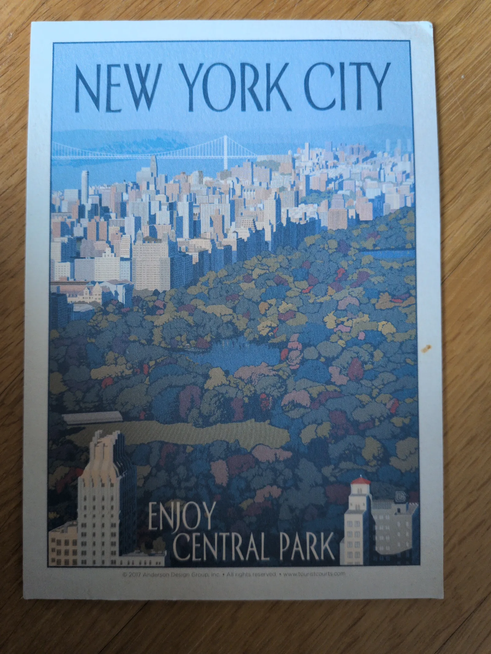 Ein stilisiertes Bild von New York City zeigt den Central Park im Vordergrund, die Skyline dahinter und ist mit "NEW YORK CITY" sowie "ENJOY CENTRAL PARK" beschriftet.