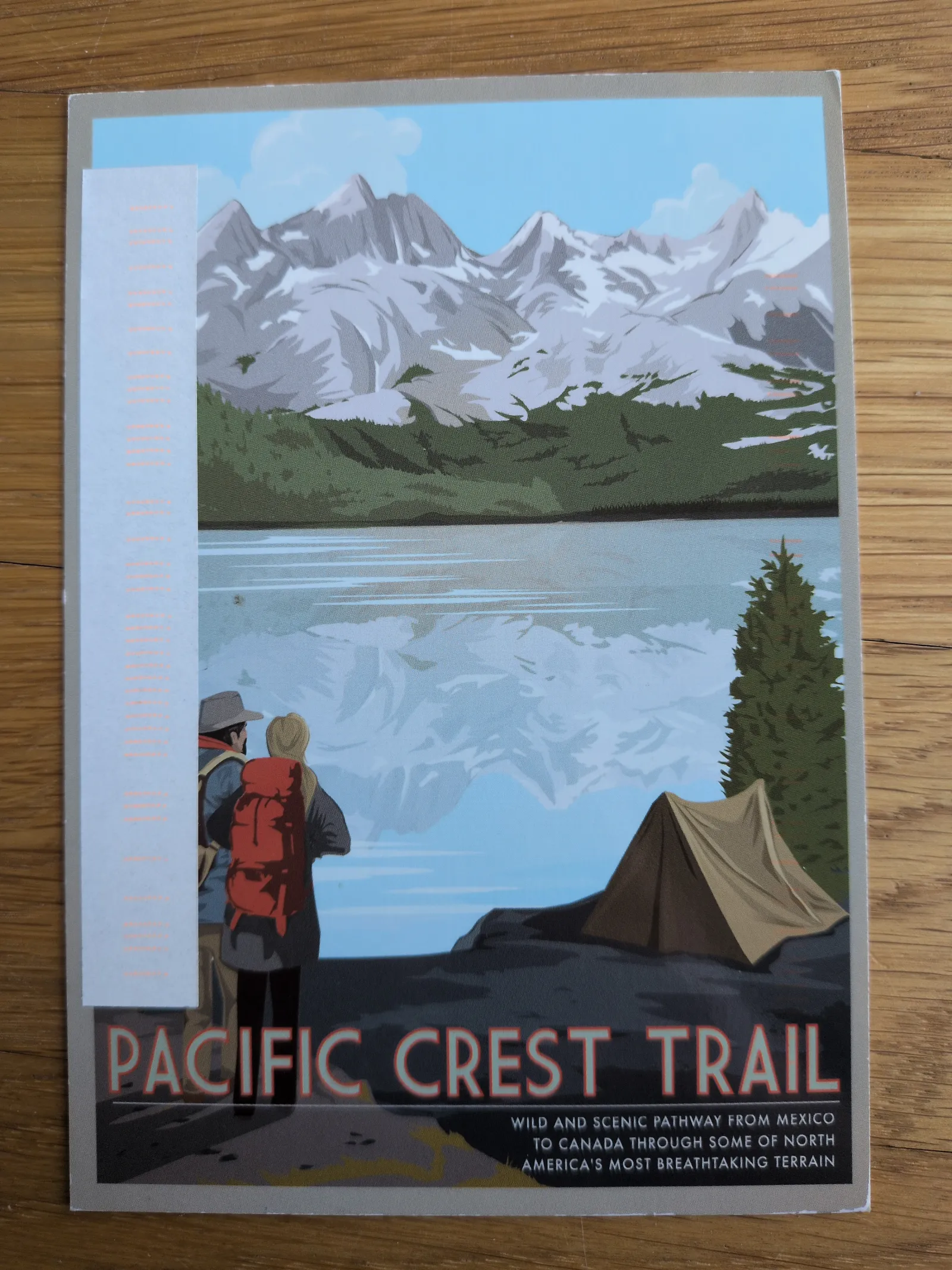 Ein stilisiertes Poster zeigt eine Berglandschaft mit See, zwei Wanderern, einem Zelt und dem Schriftzug "Pacific Crest Trail".