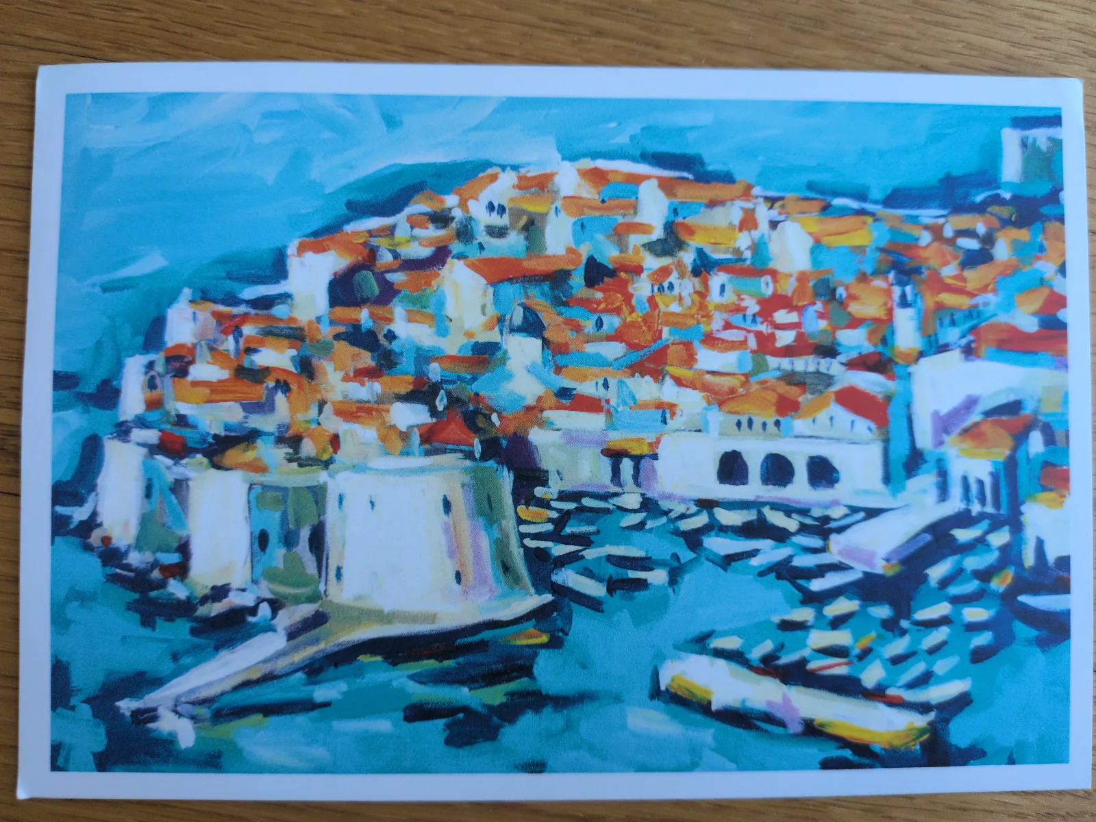 Ein farbenfrohes, impressionistisches Bild zeigt eine Küstenstadt mit orangefarbenen Dächern, blauem Wasser und Booten.