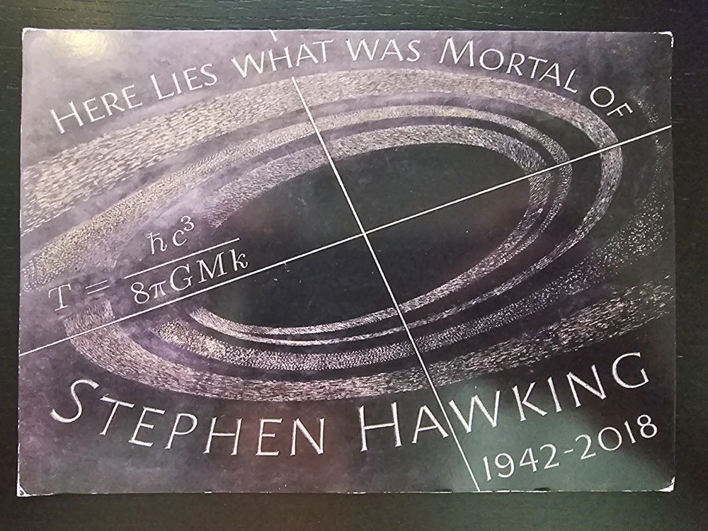 Ein dunkles Gedenkbild für Stephen Hawking mit der Aufschrift „HERE LIES WHAT WAS MORTAL OF STEPHEN HAWKING 1942-2018“, einer physikalischen Formel und einem galaktischen Ringmuster.