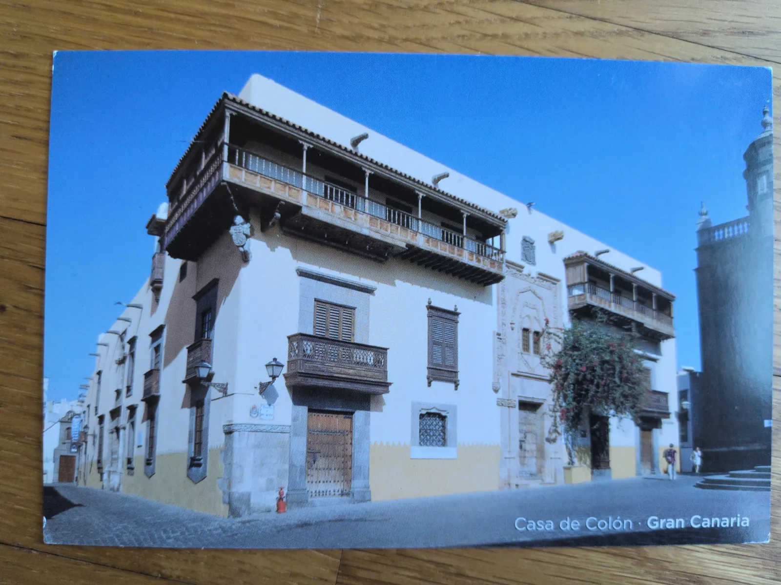 Die Casa de Colón auf Gran Canaria ist ein helles, historisches Gebäude mit dunklen Holzbalkonen an einer Kopfsteinpflasterstraße unter blauem Himmel.