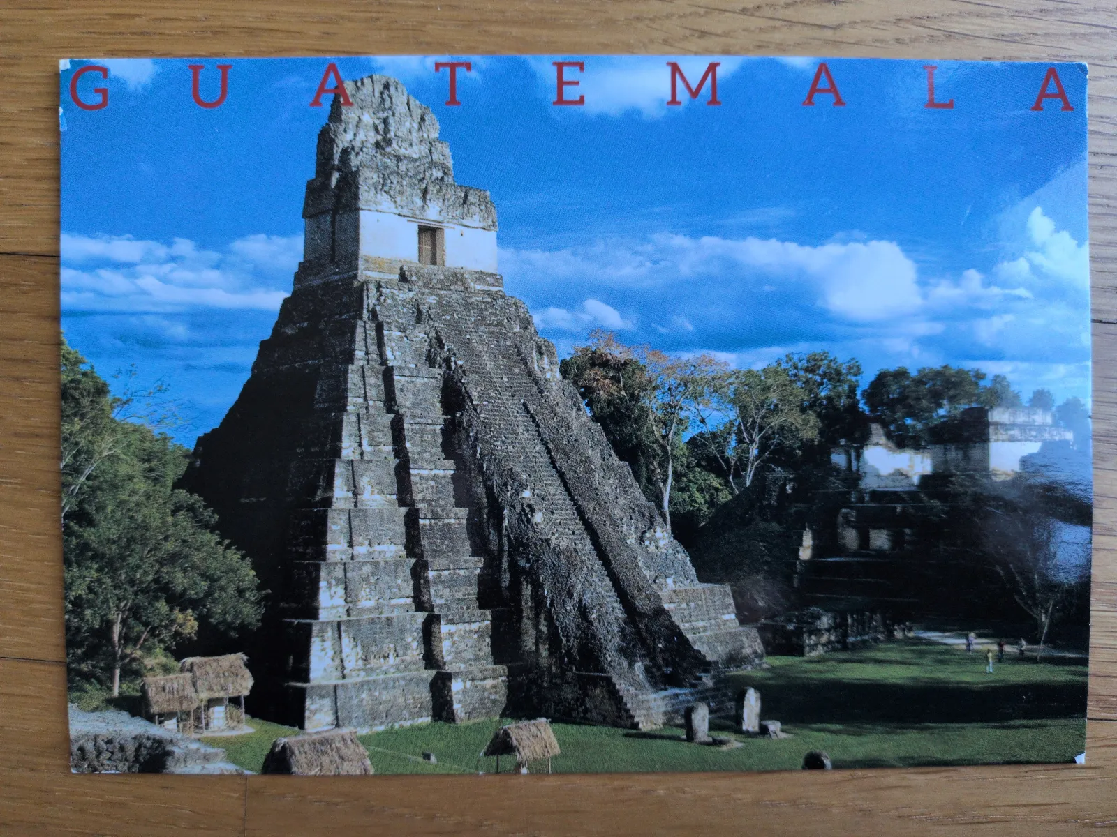 Eine imposante, stufenförmige Maya-Pyramide ragt inmitten von Dschungel in Guatemala in den blauen Himmel.
