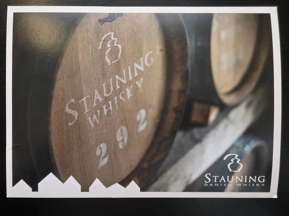 Ein hölzernes Whiskyfass mit der weißen Aufschrift „STAUNING WHISKY 292“ lagert in einem dunklen Keller.