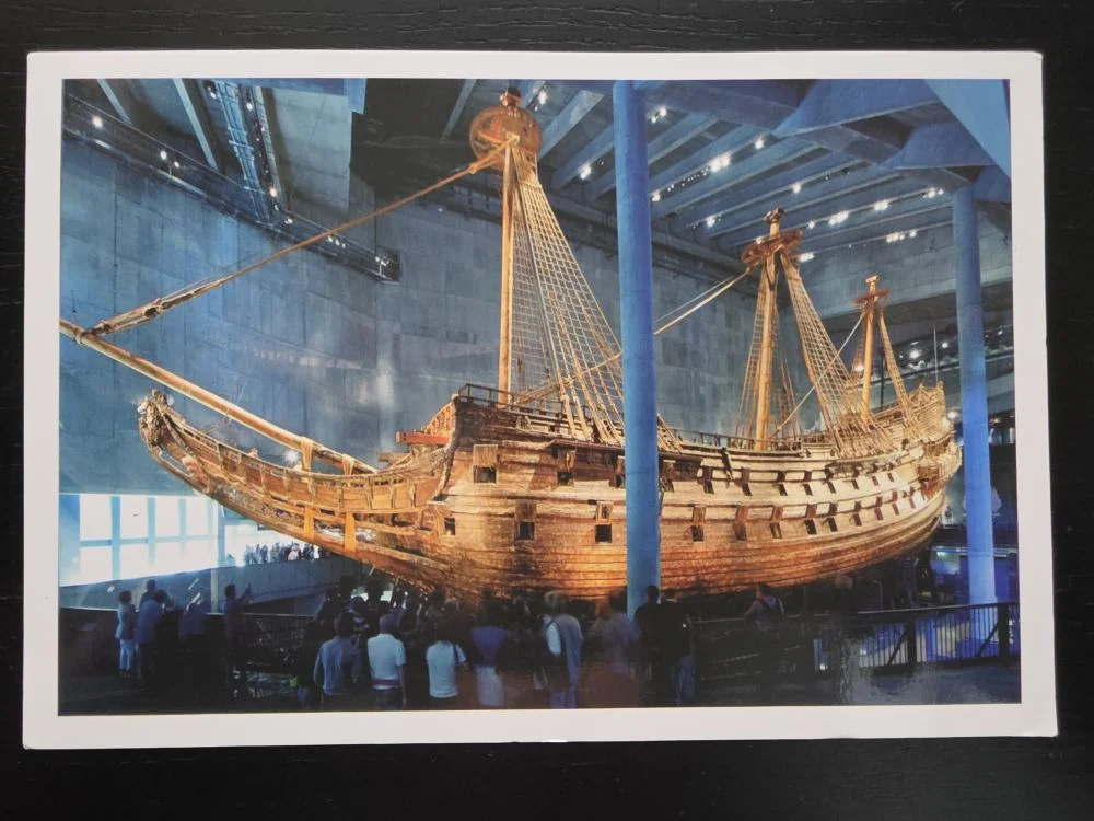 Das gewaltige historische Holzschiff Vasa steht in einer blau beleuchteten Museumshalle und wird von zahlreichen Besuchern bestaunt.