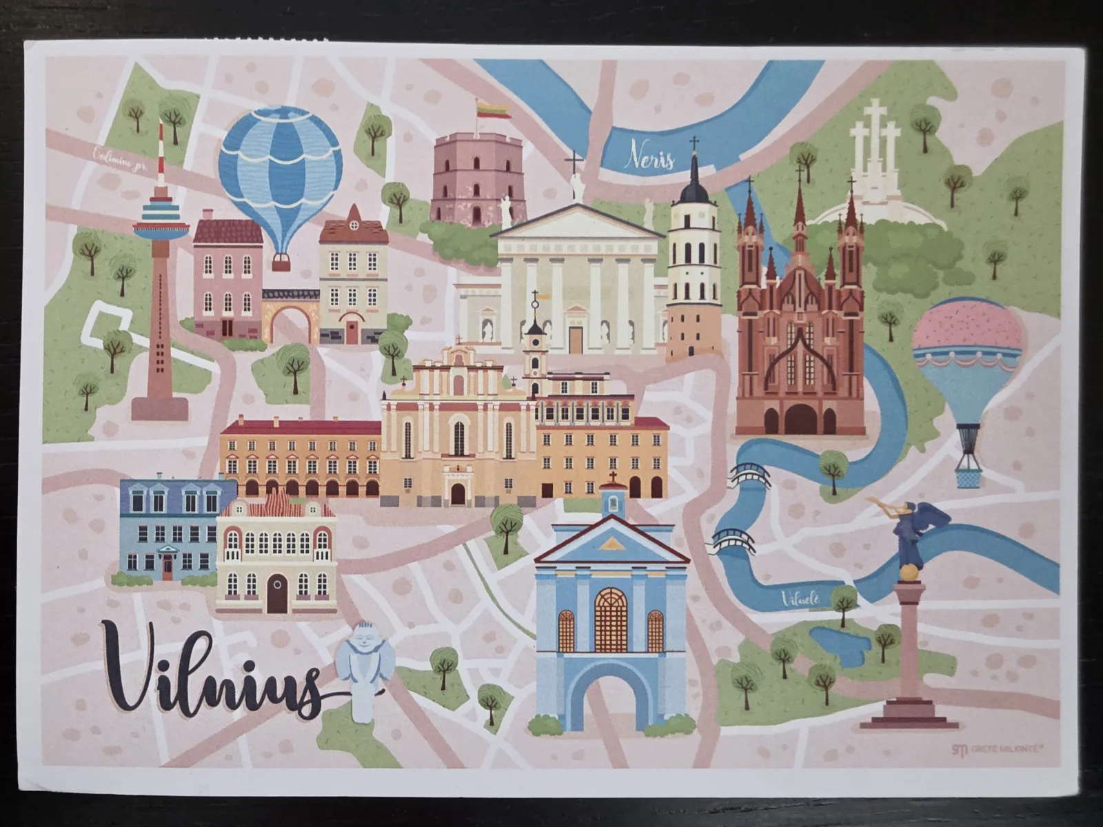 Eine illustrierte Stadtkarte von Vilnius im verspielten Postkartenstil, die bekannte Sehenswürdigkeiten, Flüsse und Heißluftballons in sanften Pastelltönen zeigt.