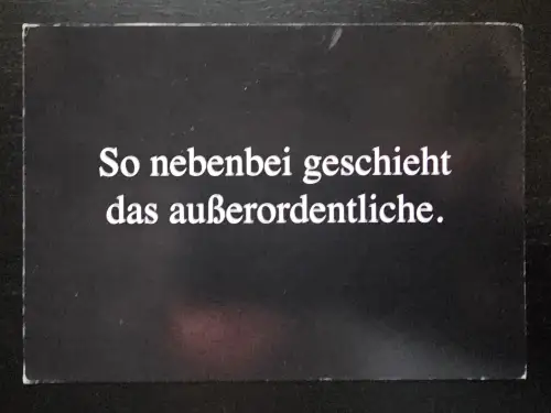 Eine dunkle Karte, auf der in weißer Schrift der Spruch: „So nebenbei geschieht das außerordentliche.“ steht.