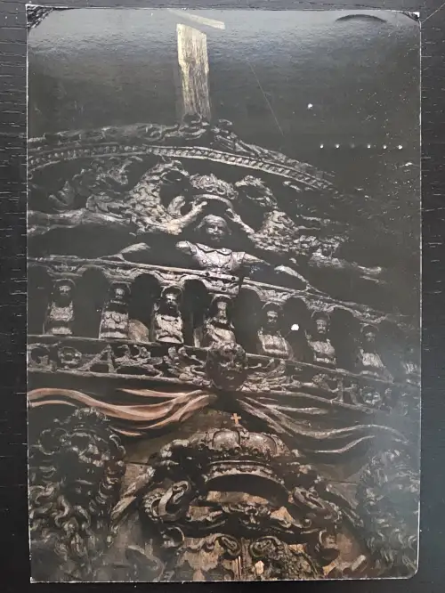 Eine dunkle, detailreiche Holzschnitzerei am Heck der Vasa zeigt eine Krönungsszene, Reihen von Figuren und üppige barocke Verzierungen.