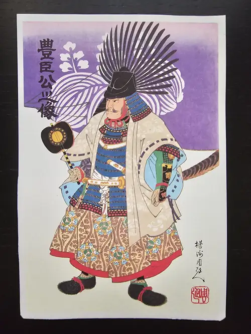 Ein farbiger japanischer Holzschnitt zeigt einen Samurai in Rüstung mit einem Fächerhut und einem Handfächer vor lila Hintergrund. Es ist Hideyoshi Toyotomi.