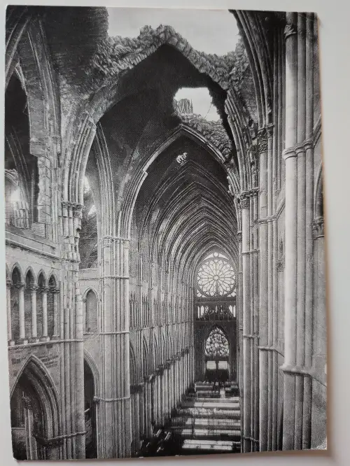 Schwarz-Weiß-Ansicht des Inneren der gotischen Kathedrale  von Reims mit hohen Säulen und Gewölben, deren Decke teilweise eingestürzt ist und den Himmel freigibt.