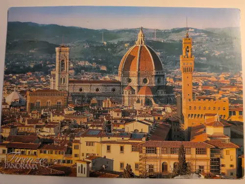 Ein Panorama von Florenz zeigt den großen Dom mit seiner roten Kuppel, Giottos Glockenturm und den Palazzo Vecchio, umgeben von unzähligen Gebäuden mit roten Dächern und grünen Hügeln im Hintergrund.