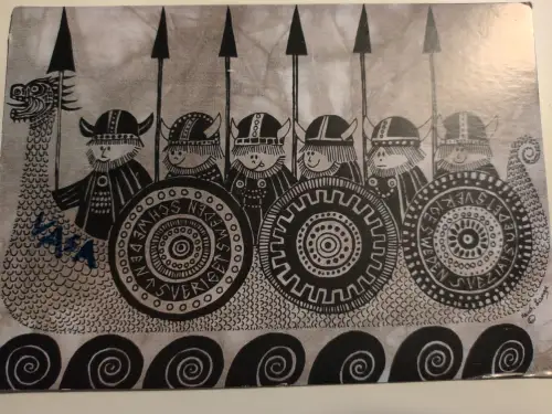 Ein stilisiertes, schwarz-weißes Bild zeigt ein Wikingerschiff mit Drachenkopf und sechs comicartigen Wikingern, die Speere und gemusterte Schilde mit der Aufschrift „SVERIGE“ tragen.