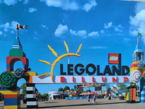 Ein großer, bunter Eingangsbogen aus Lego-Bausteinen mit dem Schriftzug „LEGOLAND BILLUND“ empfängt Besucher unter blauem Himmel.