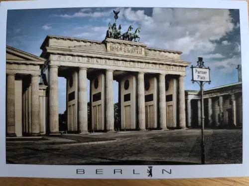 Das Bild zeigt das Brandenburger Tor in Berlin mit der Quadriga auf dem Dach und einem Schild zum Pariser Platz.