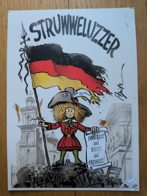 Ein Cartoon zeigt eine Struwwelpeter-ähnliche Figur, die eine Deutschlandfahne und eine Schriftrolle mit "Einigkeit und Recht und Freiheit!" auf einem Trümmerhaufen hält, über ihr steht "STRUWWELUZZER".