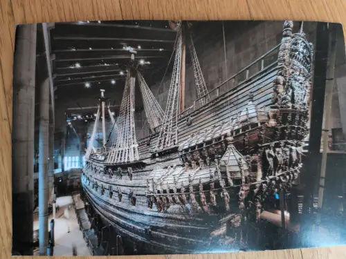 Das Bild zeigt das riesige, reich verzierte Holzschiff Vasa mit Masten und Takelage, ausgestellt in einem Museum.