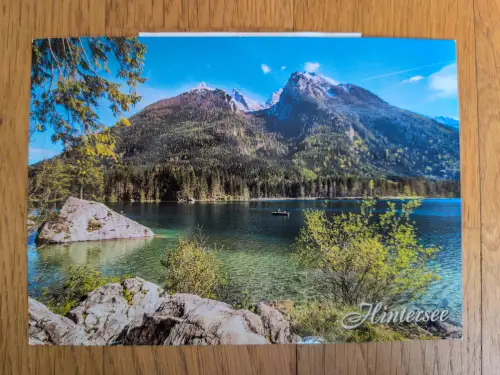 Der klare Hintersee mit einem kleinen Boot ist umgeben von bewaldeten Bergen und schneebedeckten Gipfeln.