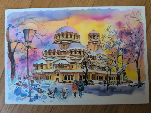 Ein farbenfrohes Aquarell zeigt eine verschneite Winterlandschaft mit einer großen Kathedrale mit schneebedeckten Kuppeln, einem Spaziergängerpaar mit Hund und Vögeln unter einem leuchtenden Himmel.