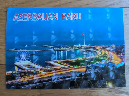 Das Bild zeigt eine nächtliche Ansicht von Baku, Aserbaidschan, mit einem beleuchteten Riesenrad, einer Flagge und Uferpromenaden, überschrieben mit "AZERBAIJAN BAKU".
