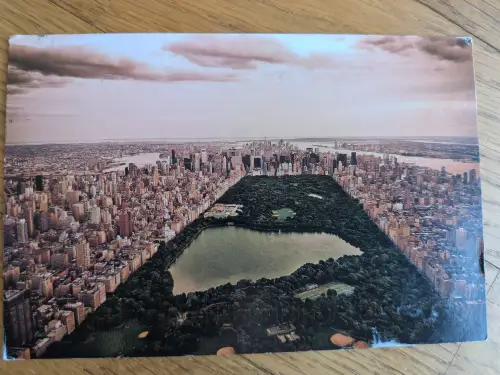 Luftaufnahme des New Yorker Central Parks, umgeben von Wolkenkratzern, mit einem großen See und Flüssen im Hintergrund.