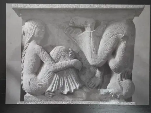 Ein steinernes Relief zeigt eine sitzende Meerjungfrau mit langem Zopf und ein geflügeltes Wesen.