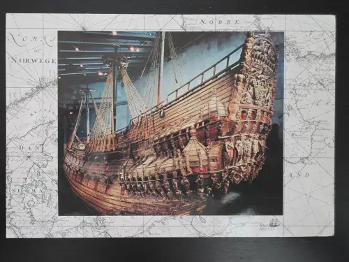 Eine Postkarte zeigt das reich verzierte Heck des historischen Holzschiffs Vasa vor dem Hintergrund einer alten Seekarte.