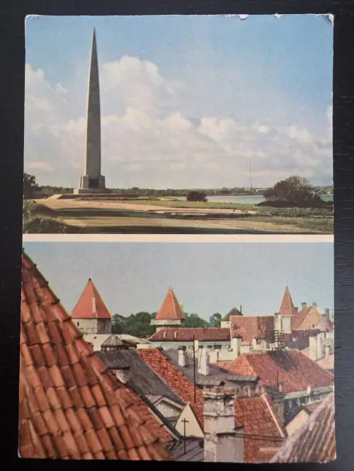 Eine zweigeteilte Postkarte zeigt oben einen hohen Obelisken in einer Küstenlandschaft und unten den Blick über die roten Ziegeldächer und mittelalterlichen Türme einer Altstadt.